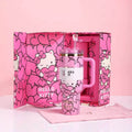 Pink 'Hello Kitty' mug with handle and straw in a matching pink box on a light pink background