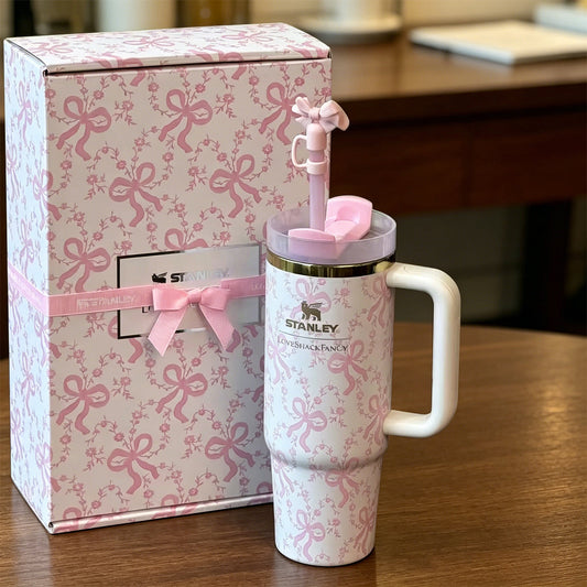 Pink and white Stanley tumbler with matching bow-themed packaging on a wooden surface.