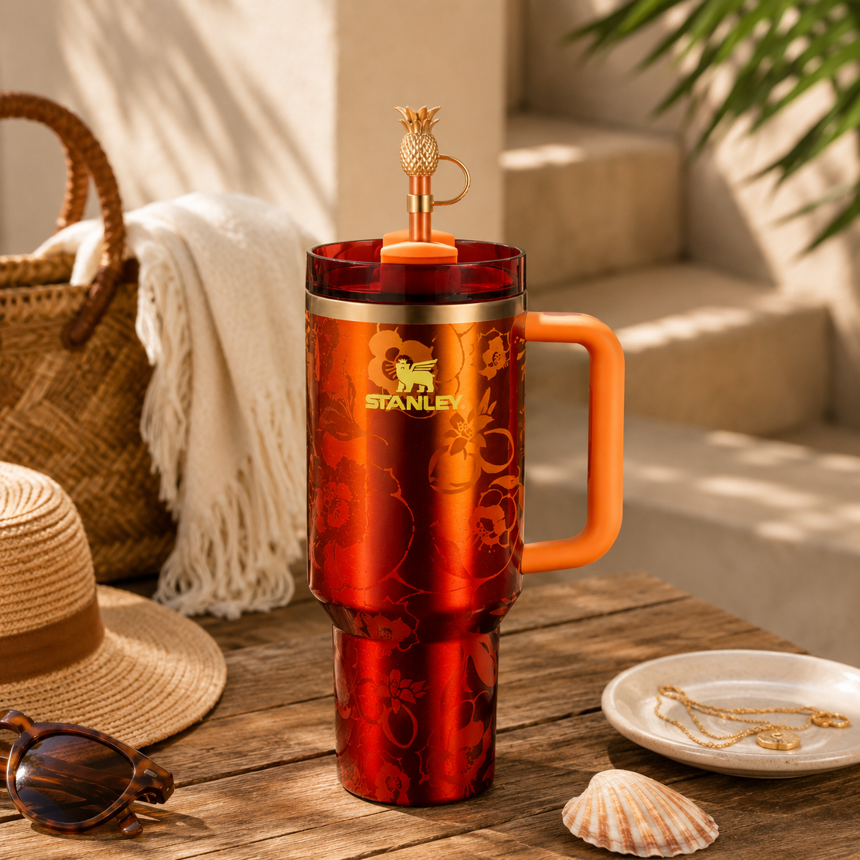 Red Stanley tumbler with a pineapple spout on a wooden table outdoors.