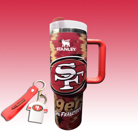 Stanley San Francisco 49ers travel tumbler with a red handle, shown with a matching red keychain and white jersey-shaped key tag on a pink gradient background.