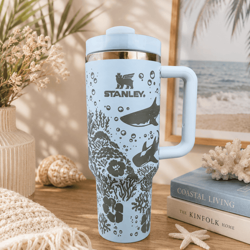 Stanley mug with ocean design on a table with books and decor