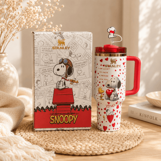 Stanley tumbler with Snoopy design next to its packaging on a wooden surface.