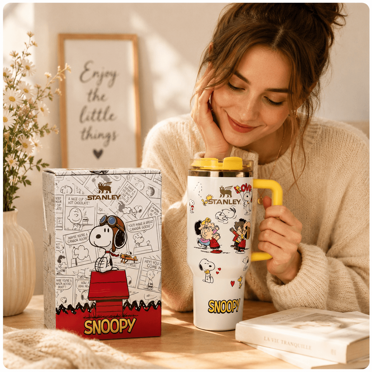 Woman holding a Snoopy-themed mug with a matching box on a table.