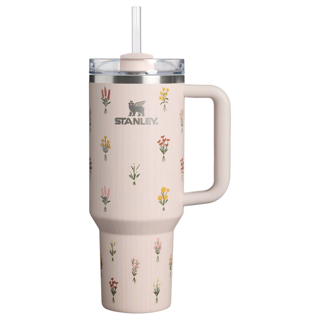 Stanley 40oz insulated tumbler featuring delicate wildflower illustrations, soft blush pink finish, white ergonomic handle, and insulated design